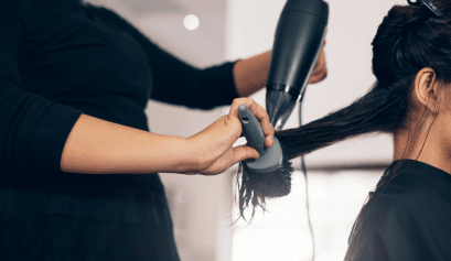 A stylist gives her client a blowout, a safe procedure that's made safer by having cosmetology liability insurance.