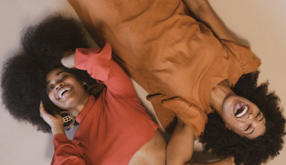 Two black stylists laugh and discuss the best ways to celebrate Black History Monday in their salons.