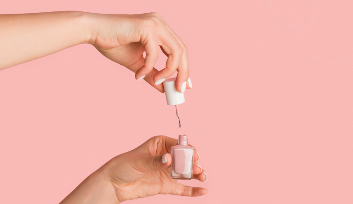 A cosmetologist holds a nail polish bottle against a pink backdrop as she considers how to balance self-care and her career.