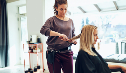 A female beauty pro works on her clients hair, showing off her skills as one of the top women in beauty in 2023.
