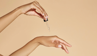 A professional cosmetologist drops a bit of her homeopathic serum on her hands.