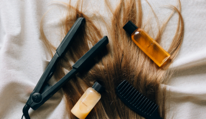 A wave of brown hair is shown with beauty products laid against it, all things beauty pros want to know if they can beauty business expense them.