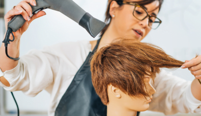 A cosmetologist works on a model during her first cut in her cosmetology program.