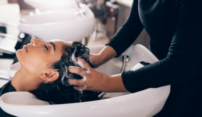 A hispanic stylist washes her clients hair in a sink during National Hispanic Heritage Month.