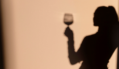 A shadow is shown of a stylist holding a glass of wine at her salon bar.