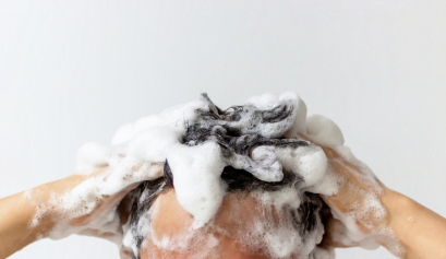 A male client washes his hair in the shower with shampoo, a men's beauty product he picked up at his local shop.